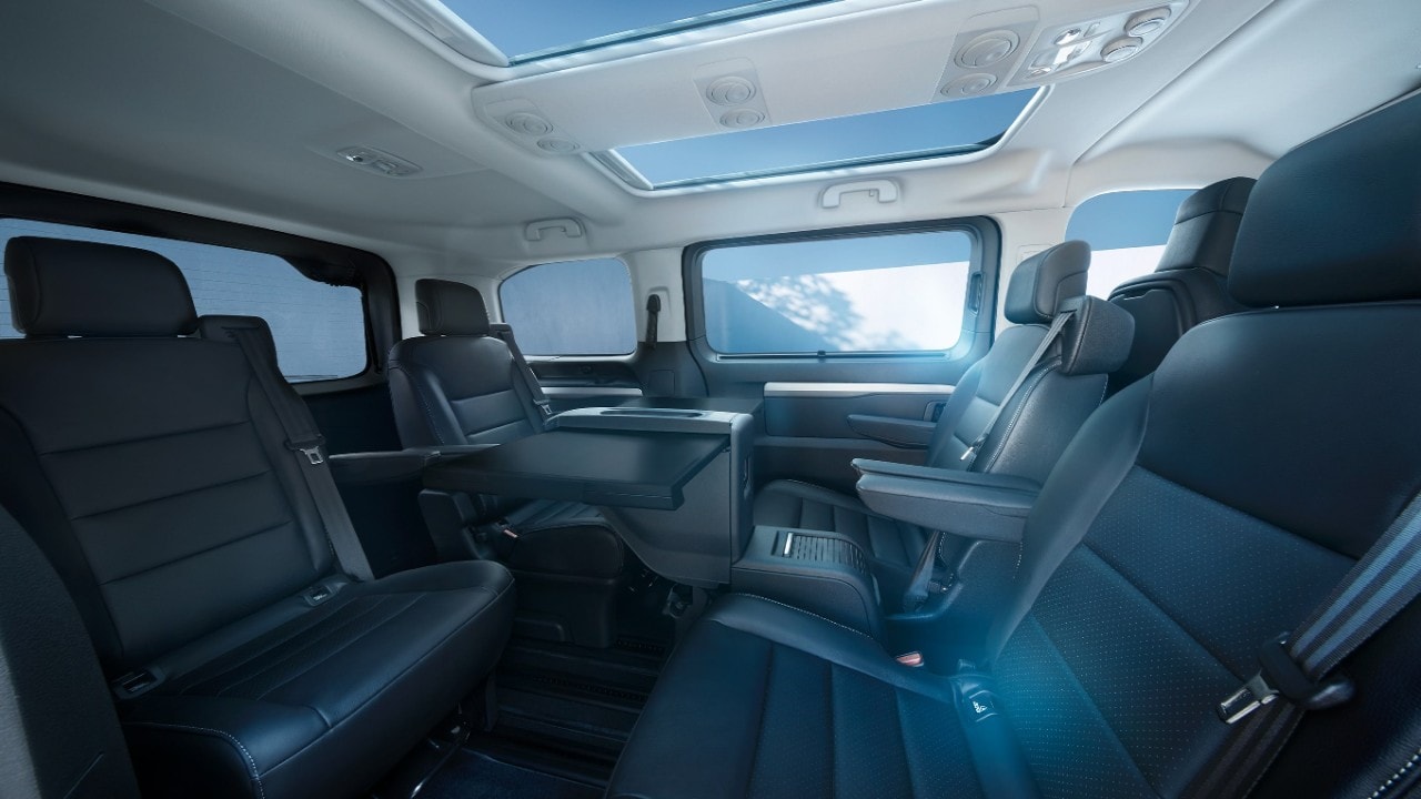 Vue intérieure d'une Opel Zafira Electric blanche depuis le siège passager avec une femme debout à l'extérieur